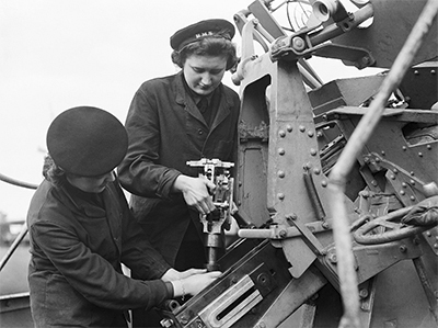 Miembros del WRNS haciendo el mantenimiento de un cañón naval. Imagen de dominio público. Autor: Royal Navy official photographer, Tomlin, H W (Lt)